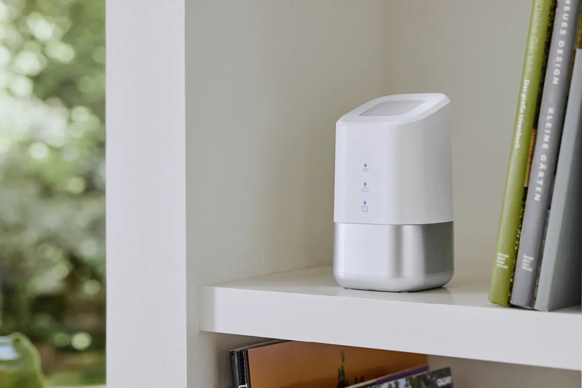 Weiße Homematic IP Home Control Unit auf einem Regal neben Büchern